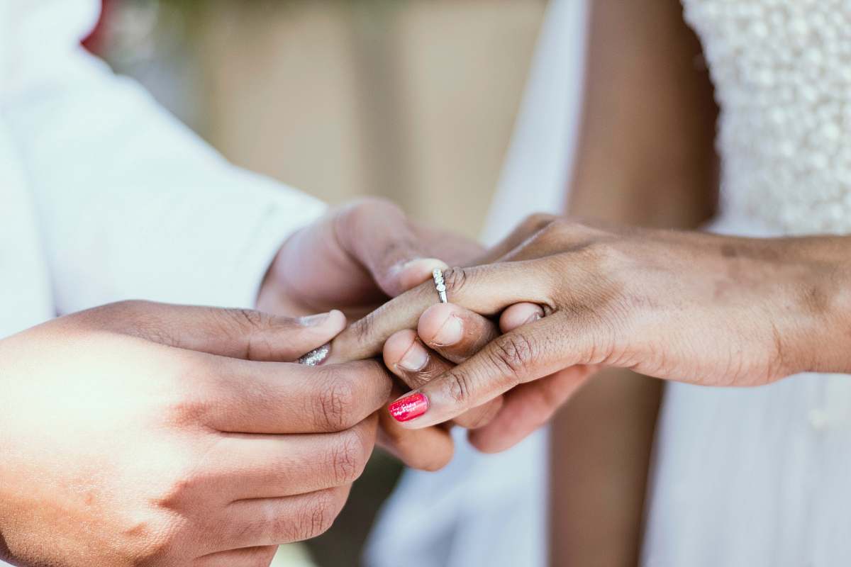 holding hands person putting ring on ring finger of woman wedding